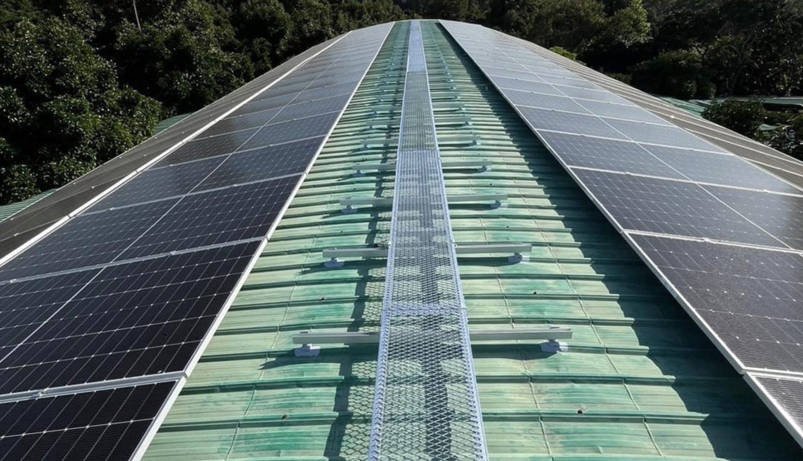 ผลงานติดตั้ง สวนสุภัทราแลนด์ ระยอง 100 kWp — ภาพรวมแผงสองฝั่งหลังคาพร้อมทางเดินตรวจสอบ